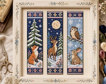 May include: Three vertical cross-stitch bookmarks framed in a light-colored wooden frame. The left bookmark shows a fox in snow with a pine tree. The center shows a deer under a full moon. The right shows an owl and a rabbit in a snowy scene.