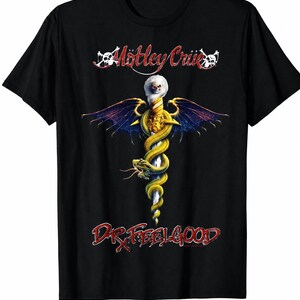以下が含まれることがあります： 黒の半袖Tシャツ。紫の翼と頭部に髑髏をあしらった銀色の剣に、黄色い蛇が巻き付いているグラフィックが描かれている。グラフィックの上部には「Mötley Crüe」、下部には赤色で「DR. FEELGOOD」の文字がプリントされている。
