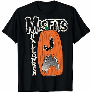 May include: A black short-sleeve t-shirt featuring a graphic of an orange pumpkin with a jagged, distressed face. The text "MISFITS" appears in a white, rough-edged font above the pumpkin, with the word "HALLOWEEN" written vertically in white.
