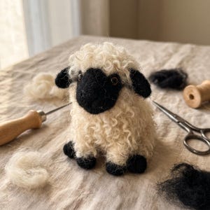 Könnte beinhalten: Eine gefilzte Schaf-Figur mit einem Körper aus cremefarbener, lockiger Wolle, einem schwarzen Gesicht, schwarzen Ohren und schwarzen Hufen. Das Schaf hat kleine dunkle Augen und ist von losen Büscheln aus schwarzer und cremefarbener Wolle umgeben.