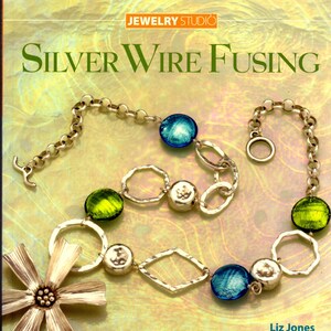 May include: A silver wire fusing necklace with green and blue glass beads, a silver flower charm, and a silver chain. The necklace is on a yellow and white background. The text "Silver Wire Fusing" and "Jewelry Studio" are visible in the image. The text "Liz Jones" is also visible in the image.