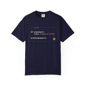 Op de afbeelding: Marineblauw T-shirt met Python-code en de tekst "Powered by Coffee", plus een afbeelding van een koffiekopje. Het shirt heeft korte mouwen en een ronde hals.