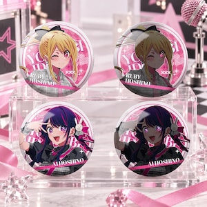 May include: Four circular pin-back buttons featuring anime-style illustrations of Ruby Hoshino and Ai Hoshino. The top two buttons show blonde Ruby Hoshino winking, while the bottom two show dark-haired Ai Hoshino making a peace sign. Each button includes text.