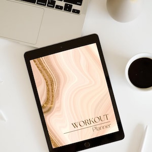 May include: A black tablet displaying a "Workout Planner" with a marble design in shades of pink and gold. The tablet is on a white surface, next to a laptop, a cup of coffee, and a small vase.