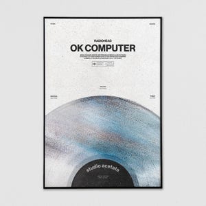 May include: A framed poster featuring the album "OK Computer" by Radiohead. The poster has a black frame and a white background with the album title in bold black letters. A stylized image of a vinyl record is at the bottom, with the words "studio acetate".
