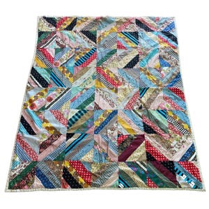 May include: A patchwork quilt with a vibrant array of colors and patterns. The quilt is composed of numerous rectangular and triangular fabric pieces, creating a geometric design. The fabrics include floral, striped, and solid patterns in various colors.