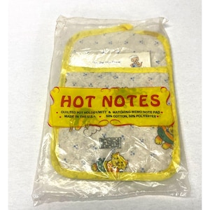 May include: A quilted pot holder and matching memo note pad set in a clear plastic package. The fabric is white with a blue floral pattern and yellow trim. A yellow label reads HOT NOTES, QUILTED POT HOLDER/MITT & MATCHING MEMO NOTE PAD.