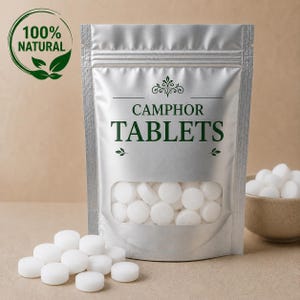 Pode incluir: Uma bolsa prateada vertical contendo pastilhas de cânfora brancas, com uma janela transparente para ver o conteúdo. O rótulo exibe o texto CAMPHOR TABLETS e um logotipo 100% NATURAL com gráficos de folhas. Várias pastilhas brancas estão à frente.