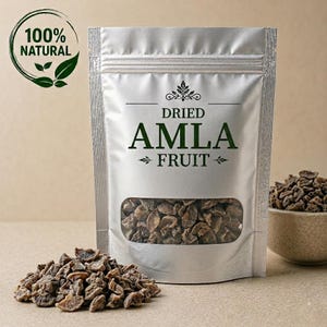 Könnte beinhalten: Ein silberner Standbeutel mit getrockneten Amla-Früchten, der ein Sichtfenster mit den dunkelbraunen Stücken enthält. Das Etikett trägt die Aufschrift "DRIED AMLA FRUIT" in dunkelgrüner Schrift und ein "100% NATURAL"-Logo oben links.