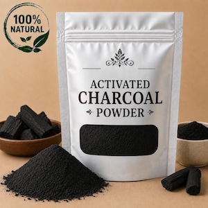 以下が含まれることがあります： ACTIVATED CHARCOAL POWDERと書かれた白いスタンドパウチ。透明な窓から黒い粉末が見える。パウチには葉が描かれた100% NATURALの円形ロゴがある。横には黒い粉末と木炭の塊が入った小さなボウルが置かれている。