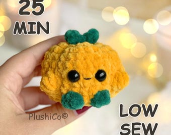 Può includere: Un piccolo peluche all'uncinetto giallo oro, rotondo e testurizzato, con due dettagli a forma di foglia verde scuro sulla parte superiore, due piedini verde scuro alla base e due occhi di sicurezza in plastica nera. Testo: 25 MIN e LOW SEW.