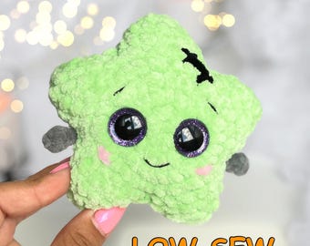 Può includere: Un peluche a forma di stella verde chiaro con una superficie morbida e testurizzata. Presenta grandi occhi rotondi viola glitterati, un piccolo sorriso ricamato, guance rosa e un dettaglio a punto nero sulla parte superiore.