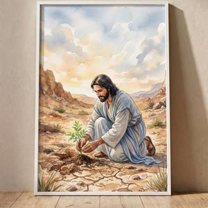 Könnte beinhalten: Ein gerahmter Aquarelldruck, der eine Figur mit langem dunklem Haar und Bart in einem hellblauen Gewand zeigt, die in einer trockenen, rissigen Wüstenlandschaft kniet und eine kleine grüne Pflanze pflegt, die aus der Erde wächst.