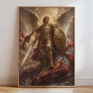 Op de afbeelding: Een ingelijste kunstdruk met een gevleugelde figuur in gouden harnas die op een rode draak staat. De figuur houdt een gloeiend zwaard en een rond schild vast, met grote witte vleugels gespreid tegen een bewolkte, gouden lucht.