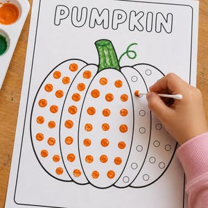 May include: A white activity sheet with the word PUMPKIN printed in black at the top. The sheet features a large pumpkin outline with circular dots, some filled with orange paint using a cotton swab, and a green colored stem.