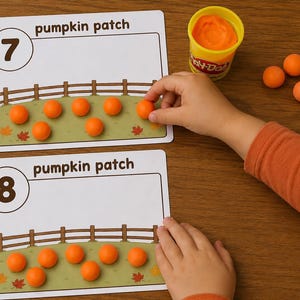 May include: Two rectangular educational cards labeled pumpkin patch with the numbers 7 and 8. Each card features a fence and green field illustration. Small orange modeling clay spheres are placed on the cards to represent pumpkins.