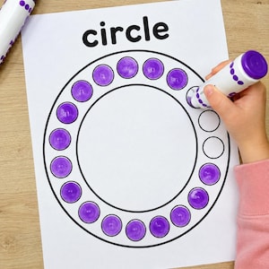 May include: A white activity sheet with the word circle printed in black at the top. A large circular outline is filled with smaller circles, many of which are colored in with a purple dot marker. A purple dot marker is held to the paper.