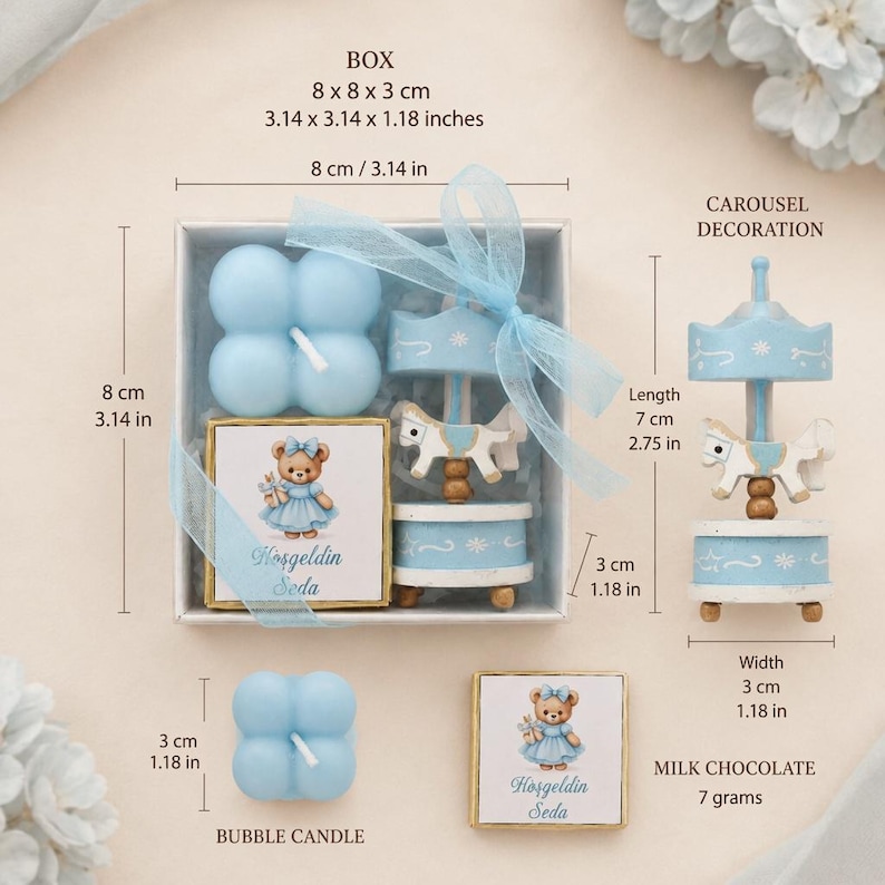 May include: A gift set containing a light blue bubble candle, a square chocolate bar with a teddy bear illustration and the text Hoşgeldin Seda, and a carousel decoration. The box measures 8 x 8 x 3 cm. The carousel is 7 cm in length.