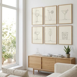 May include: A set of six framed wall art prints featuring black line drawings of various cocktail glasses, including a wine glass, a highball with a straw, a martini glass, a coupe, a champagne flute, and a rocks glass on a light background.