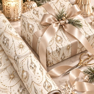 May include: A gift box wrapped in cream-colored paper featuring a pattern of gold and silver ornaments, stars, and beaded garlands, topped with a wide champagne-colored satin ribbon bow and a small sprig of pine needles and gold berries.