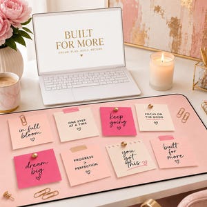May include: A light pink desk mat featuring eight square sticky notes with motivational phrases including in full bloom, one step at a time, keep going, focus on the good, dream big, progress over perfection, you got this, and built for more.
