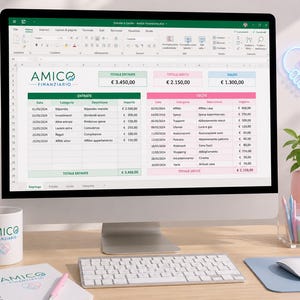 May include: A computer monitor displays a spreadsheet with financial data, including income and expenses, with the text "AMICO FINANZIARIO". A white mug and notepad with the same logo are on the desk, along with a keyboard and mouse.