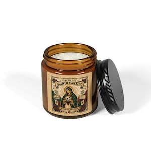 May include: A brown glass jar candle with a black lid. The label features an illustration of the Virgin Mary holding a soccer ball, with text in Spanish. The candle is unscented and has a white wax.