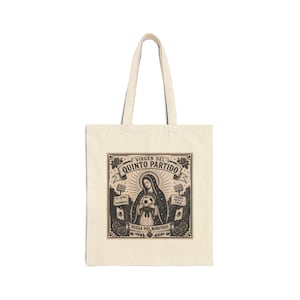 May include: Cream-colored tote bag featuring a black and white graphic. The graphic includes the text "Virgen del Quinto Partido" and an illustration of a religious figure holding a soccer ball. The bag has two handles.