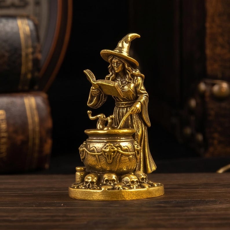 Puede incluir: Una figura de metal color lat&oacute;n que representa a un personaje con sombrero puntiagudo leyendo un libro abierto junto a un caldero. El caldero est&aacute; decorado con motivos de calaveras y descansa sobre una base rodeada de peque&ntilde;as calaveras.