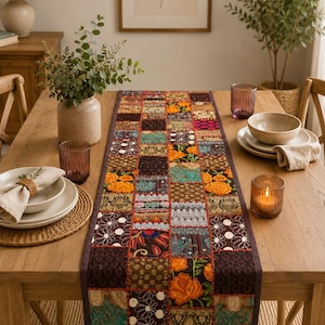 May include: A rectangular table runner featuring a patchwork design of various fabric squares in shades of orange, teal, brown, and cream. The runner displays intricate embroidery, floral patterns, and geometric motifs with visible stitching.