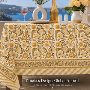 May include: A rectangular tablecloth featuring a repeating floral pattern in shades of mustard yellow and olive green on a cream background, finished with a decorative border of yellow stripes and small floral motifs along the bottom edge.