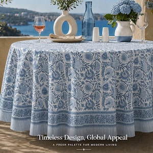 May include: A round tablecloth featuring a blue and white floral block print pattern with a striped border. The text at the bottom reads: Timeless Design, Global Appeal. A FRESH PALETTE FOR MODERN LIVING. The fabric drapes over a circular table.