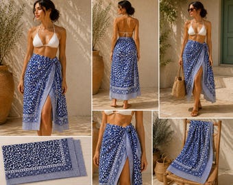 May include: A blue and white sarong featuring a dense botanical leaf pattern with a decorative border. The fabric is shown wrapped around the waist as a skirt, draped over a wooden chair, and folded flat, displaying the intricate floral print.
