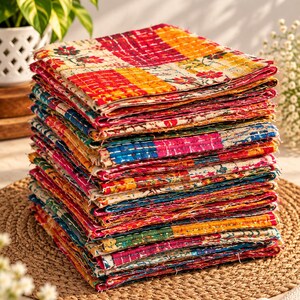 Puede incluir: Una pila alta de servilletas de tela cuadradas con un diseño de patchwork que presenta varios patrones florales y geométricos en tonos vibrantes de rojo, amarillo, azul y verde, acabadas con costuras blancas visibles por toda la superficie.
