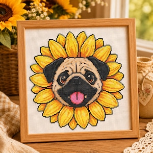 May include: A square cross-stitch embroidery in a light wood frame featuring a centered pug dog face surrounded by bright yellow sunflower petals. The pug has a black muzzle, dark ears, and a pink tongue sticking out against a white fabric background.