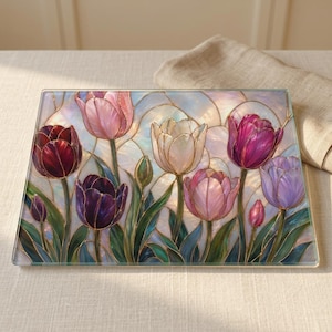 May include: A rectangular glass cutting board featuring a stained glass style illustration of tulips in shades of deep red, purple, pink, and white. The design includes dark outlines and green leaves against a pearlescent, iridescent background.