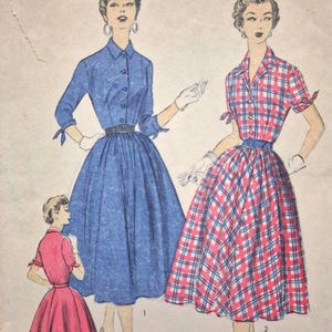 May include: A vintage sewing pattern illustration featuring three dresses. One is a solid blue dress with a collared neckline, three-quarter sleeves with ties, and a belted waist. Another is a red, white, and blue plaid dress with short sleeves and a belt.