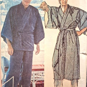May include: A sewing pattern envelope featuring a photograph of a solid navy blue wrap-style robe and matching trousers, alongside a sketch of a patterned robe with a diamond motif. The text John Weitz is printed at the bottom of the envelope.
