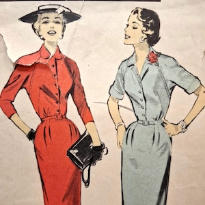 Op de afbeelding: Een vintage naaipatroonillustratie met twee figuren in doorknoopjurken met ceintuur. Het linkerfiguur draagt een rode jurk en een zwarte hoed, terwijl het rechterfiguur een lichtblauwe jurk met een rode bloem draagt.