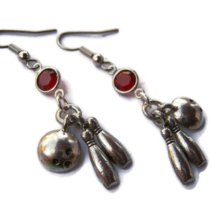 Puede incluir: Pendientes de plata con detalles de cristal rojo y abalorios de bola de bolos y bolos.