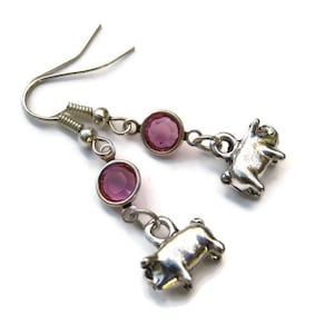 Puede incluir: Pendientes de plata con forma de cerdo con detalles de cristal rosa. Los encantos de cerdo son detallados y los cristales son redondos.