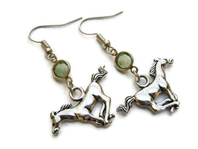 May include: Silver horse earrings with green gemstone accents. The horse charms are in a running pose.