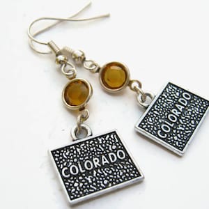 May include: A pair of silver earrings with amber-colored glass beads and silver charms that say "COLORADO".
