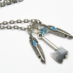 May include: A silver necklace with a small axe charm, two blue and silver feathers, and a blue crystal bead.