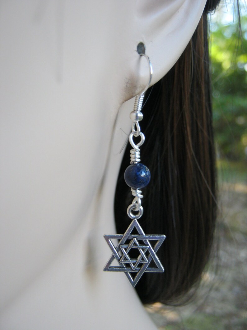 Pu&ograve; includere: Orecchini pendenti in argento con un ciondolo a forma di stella di David in argento e una perla di lapislazuli blu.