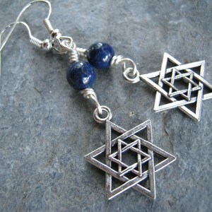 Pu&ograve; includere: Orecchini d'argento con un ciondolo a forma di stella di David in argento e una perla di lapislazuli blu.