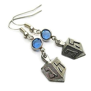 Puede incluir: Pendientes colgantes plateados con detalles de piedras preciosas azules y dijes de dreidel. Los pendientes tienen un cierre de gancho. Los dijes de dreidel son plateados y tienen las letras hebreas Nun, Gimmel, Hei y Shin.