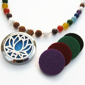 May include: A silver aromatherapy necklace with a lotus flower design, a blue felt pad, and a beaded chakra necklace. Includes several colorful felt pads in purple, burgundy, green, and black. The necklace features a variety of colorful beads.