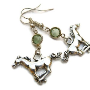 May include: Silver tone earrings with green glass stones and a horse charm. The horse is running.