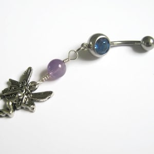 May include: A silver belly button ring with a blue gem, a purple bead, and a silver fairy charm.